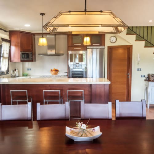Cocina moderna con muebles de madera oscura, electrodomésticos de acero inoxidable e isla con asientos en Vila Lourido, Baiona