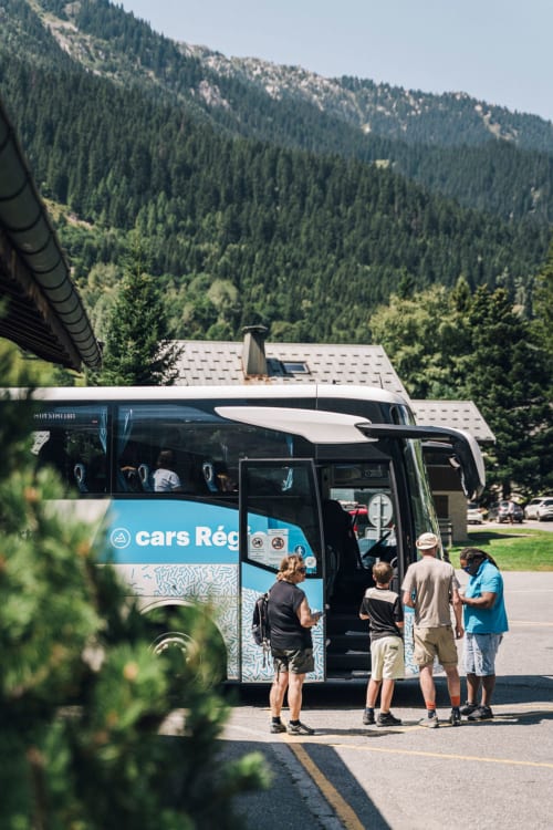Groupe embarquant dans la navette au Chalet des Cimes à Belle Plagne avec vue sur les montagnes forestières