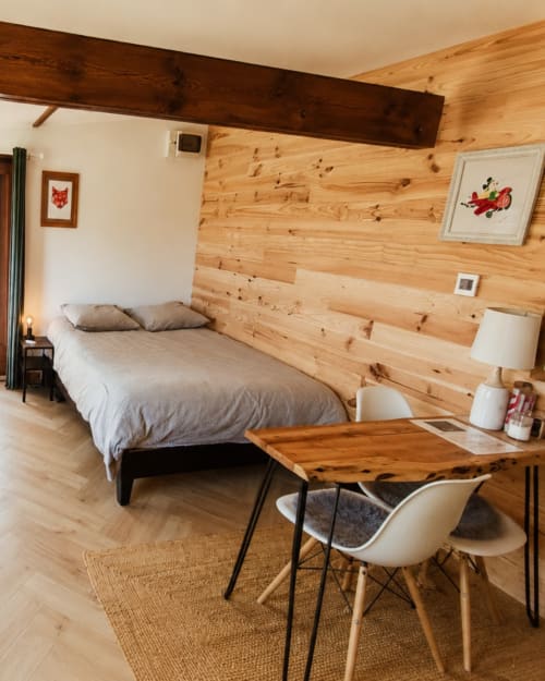 Cozy studio bedroom at Les Chalets de Mosnay with knotty pine walls, bed, desk, and wood beams