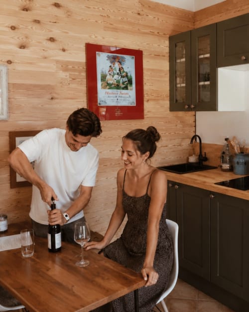 Couple opening wine in kitchen of Grand Studio cottage at Les Chalets de Mosnay, Mosnay, France
