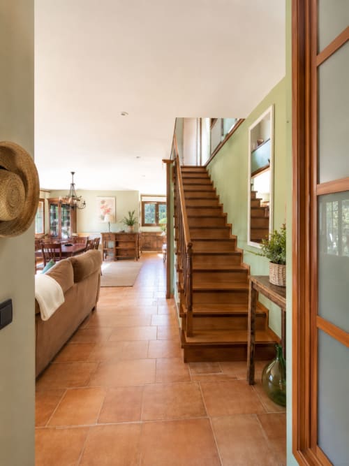 Escalera de madera con paredes verdes que conduce al piso superior en espaciosa villa de Baiona con suelo de terracota y diseño moderno