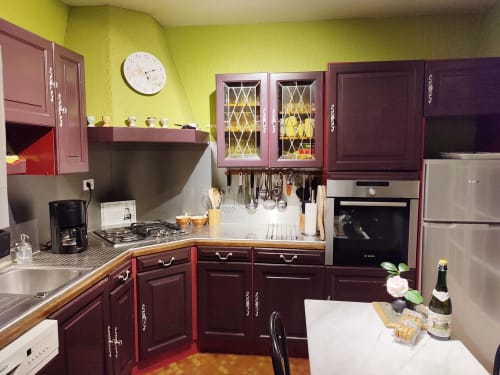 Cuisine moderne avec meubles couleur bordeaux, murs jaunes et électroménagers inox à L'effet Mer Parenthese à Pénéstin