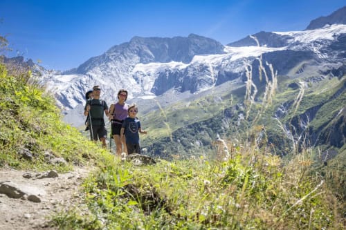 Famille en randonnée près du Chalet des Cimes à Belle Plagne avec vue sur les Alpes enneigées et la vallée