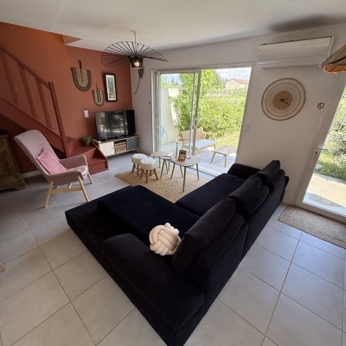 Villa moderne avec salon au canapé noir, mur accent en terre cuite et vue sur jardin aux Maisons Le Clos Du Moulin