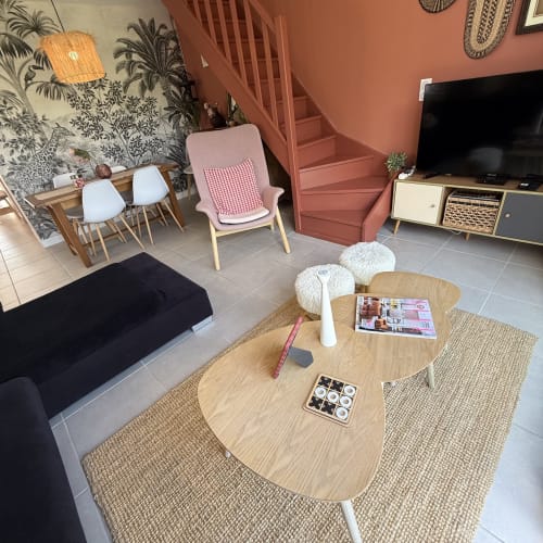 Élégant salon de villa avec table basse en bois, fauteuil rose, télévision écran plat et escalier à Entraigues sur la Sorgue