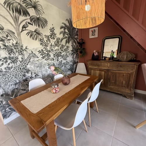 Élégante salle à manger avec table en bois, chaises blanches, papier peint botanique et murs en terre cuite aux Maisons Le Clos Du Moulin