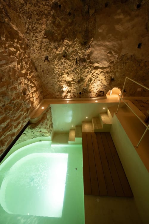 Bagno termale sotterraneo a Mileca Sciù Sciù a Sciacca con acqua luminescente verde e antiche mura in pietra