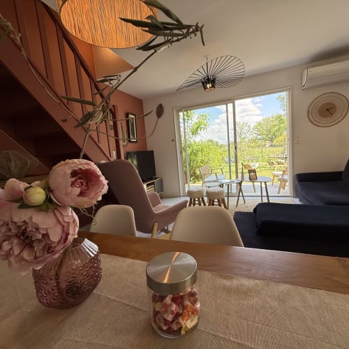 Salon moderne de villa avec pivoines roses, éclairage design et vue sur jardin aux Maisons Le Clos Du Moulin