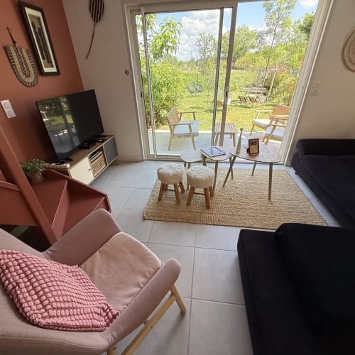 Salon moderne de villa avec fauteuil rose, portes sur jardin et coin détente patio aux Maisons Le Clos Du Moulin, Entraigues sur la
