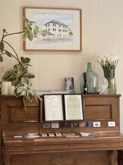 Affichage Savoy Hôtel sur piano en bois avec croquis d'architecture encadré, tulipes blanches et menus d'hôtel vintage