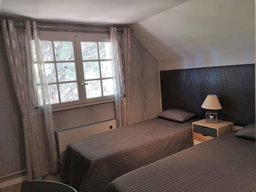 Chambre moderne à l'hôtel L'effet Mer Parenthese à Pénéstin avec deux lits, tête de lit sombre et grandes fenêtres panoramiques