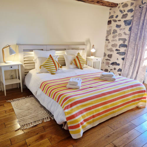 Literie à rayures colorées dans la Chambre Cocon de l'hôtel Le Mas De Rigoulac à Argences-en-Aubrac