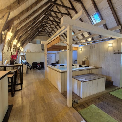 Intérieur zen au Mas De Rigoulac avec poutres en bois, bain à remous, coin détente et vue sur le jardin à Argences-en-Aubrac