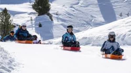 Des enfants qui font de la luge sur les pentes enneigées du Chalet des Cimes à Belle Plagne, Alpes françaises