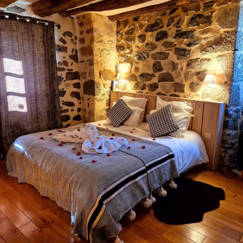 Chambre romantique au Mas De Rigoulac avec murs en pierre, poutres en bois et lit décoré à l'hôtel d'Argences-en-Aubrac
