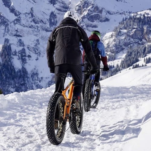 Deux motards robustes roulant sur un sentier enneigé en montagne près du Chalet des Cimes, Belle Plagne
