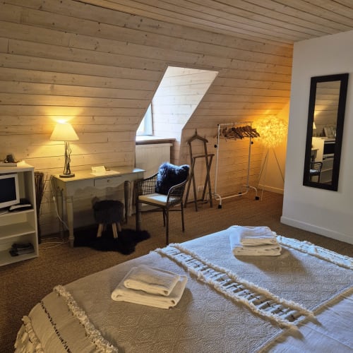 Chambre cosy sous les toits au B&B Le Mas de Rigoulac avec plafond en bois, puits de lumière, bureau, chaise et serviettes soigneusement rangées