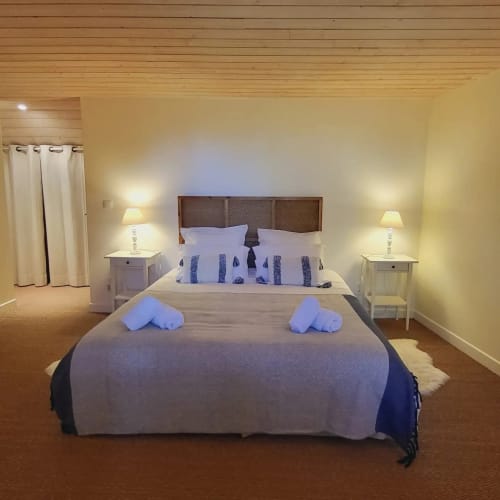 Chambre élégante du Mas De Rigoulac avec lit queen, tête de lit en bois, lampes de chevet et rideaux crème à Argences-en-Aubrac