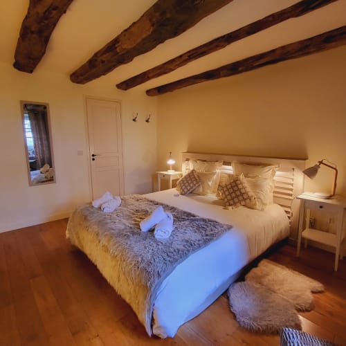 Chambre cosy au Mas De Rigoulac avec poutres apparentes, lit queen, décor blanc et vue sur le jardin à Argences-en-Aubrac