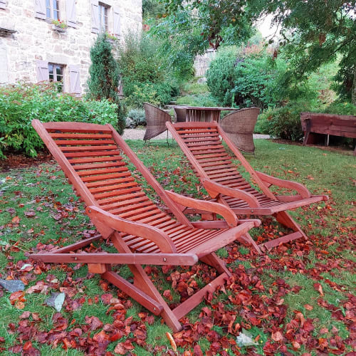 Chaises longues en bois rouge dans le jardin du Mas De Rigoulac, un gîte français en Aubrac