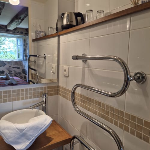 Salle de bains moderne avec sèche-serviettes chauffants, carrelage blanc métro, étagère en bois et bouilloire au Mas De Rigoulac