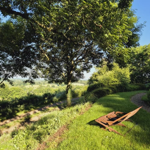 Lit en métal rustique dans un verdoyant jardin du Mas de Rigoulac, Argences-en-Aubrac