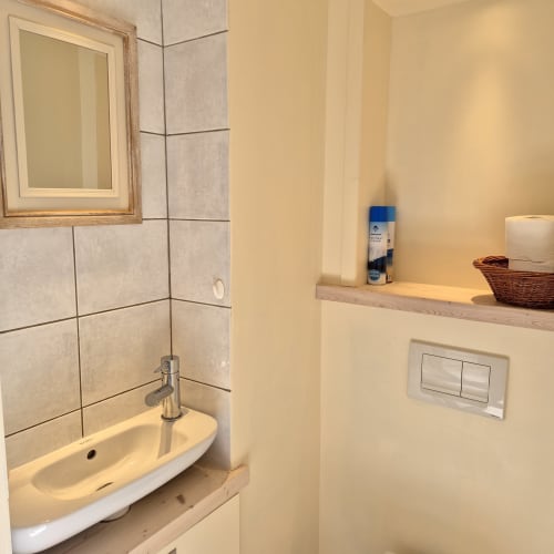 Salle de bain du gîte Le Four au Mas De Rigoulac avec lavabo, miroir, carrelage mural et étagère de toilettage
