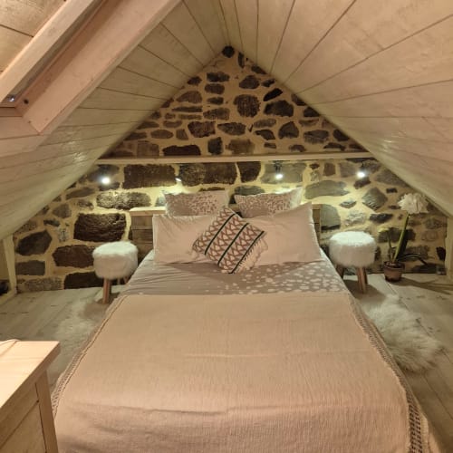 Chambre mansardée douillette au Mas De Rigoulac avec murs en pierre, poutres en bois, lit queen-size et éclairage ambiant