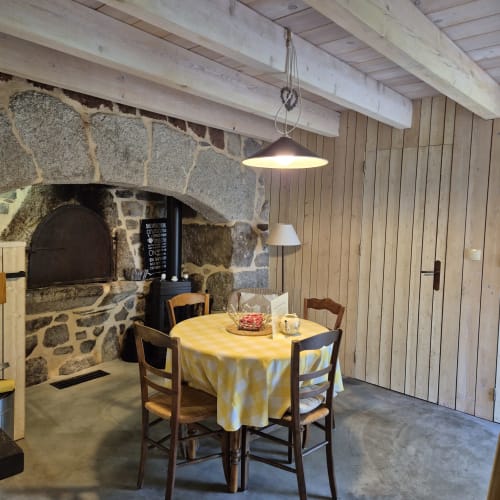 Foyer en pierre rustique dans la salle à manger avec nappe jaune au gîte Le Mas De Rigoulac, Argences-en-Aubrac