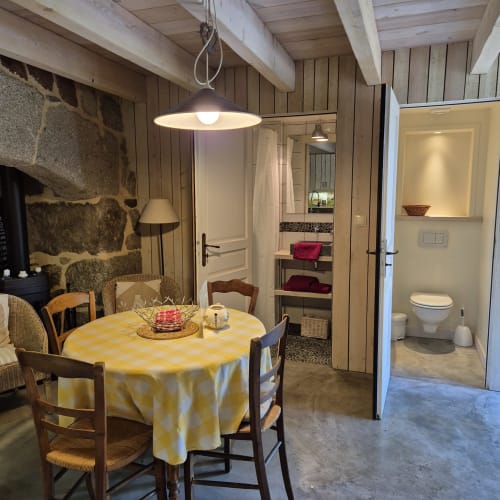 Salle à manger cottage avec nappe à carreaux jaunes, poutres rustiques en bois, foyer en pierre et espace ouvert