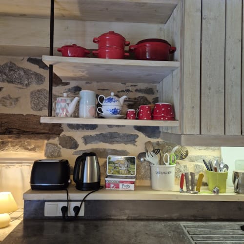 Étagères de cuisine du gîte Le Mas De Rigoulac avec ustensiles rouges, théière, accessoires et appareils électroménagers
