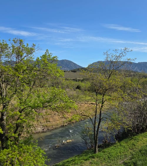 Rivière traversant une végétation verdoyante avec montagnes en arrière-plan près de l'hôtel Mas le Châtelet à Saint Paul de Fenouillet
