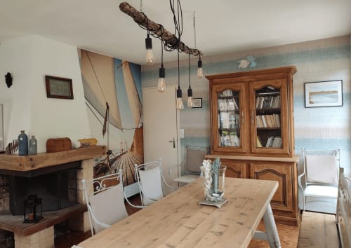 Salle à manger de la villa La Case de mon père à Penestins, avec table en bois, cheminée et suspensions au style nautique