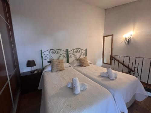 Dos camas gemelas con sábanas blancas en un dormitorio luminoso de la casa rural Casa de la Aguadora en Iznatoraf, España