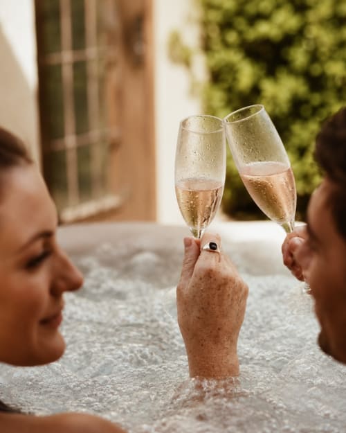 Couple trinquant au champagne dans la piscine des Chalets de Mosnay, hôtel de charme en France