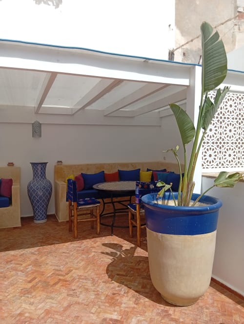 Chambre de la cour du Riad Le Village Mogador avec jardinière bleue, canapé et puits de lumière à Essaouira