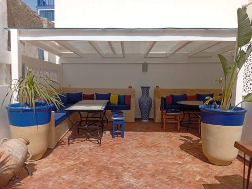 Cour intérieure du Riad Le Village Mogador à Essaouira avec bacs bleus, sièges confortables et stores rétractables