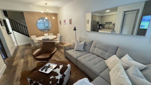 Modern Whistler apartment living room with gray sofa, dining area, and mountain view from round window