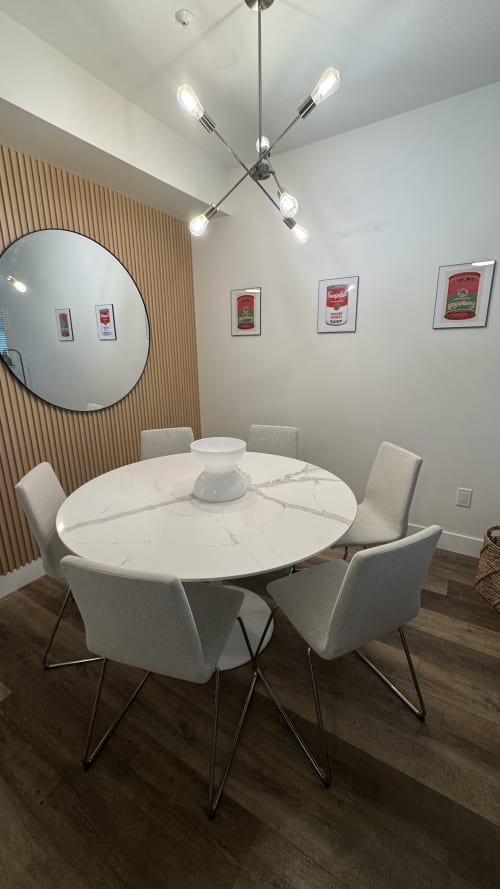 Modern dining area in Whistler apartment with round marble table, four cream chairs, chrome pendant light, and Campbell's