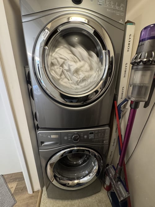 Stacked washer and dryer unit in Northstar 60 apartment at Whistler property with white linens visible in upper machine.