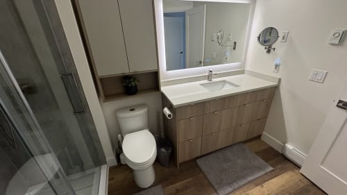 Modern bathroom in Whistler apartment with vanity, toilet, mirror, and wood cabinetry at WB Hospitality Management