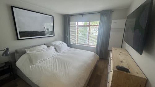 Bright mountain view bedroom in Whistler apartment with white bed, flat screen TV, large windows, and modern furnishings