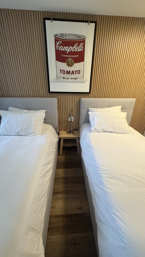 Twin beds with white linens in Whistler apartment, Campbell's Tomato Soup pop art above nightstand