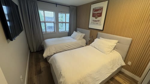 Two queen beds in modern Whistler apartment with mountain view, wallpapered accent wall, and Campbell's tomato soup artwork