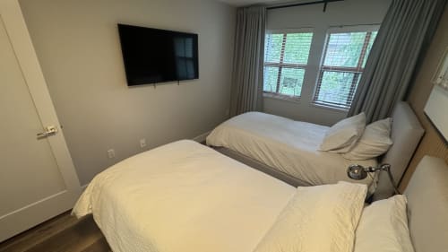 Twin beds in Northstar 60 apartment at Whistler with flat-screen TV and mountain views through balcony windows