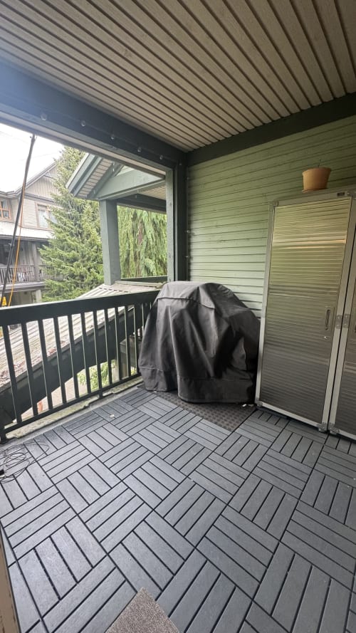 Covered balcony at Northstar 60 Whistler with dark deck, black railing, green siding, and mountain views
