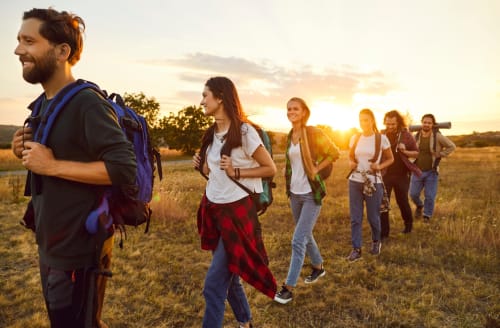 Gruppo di escursionisti che camminano attraverso un campo al tramonto vicino a un hotel a Pesaro, Italia