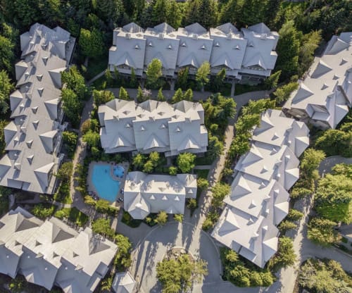 Aerial view of Whistler resort with modern townhouses, shared pool, and surrounding forest trees