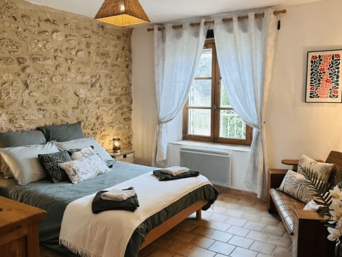 Elegantes Schlafzimmer im Domaine Bellavigne mit Steinmauern, komfortablem Bett, Glastüren und modernen Annehmlichkeiten in Forcalquier