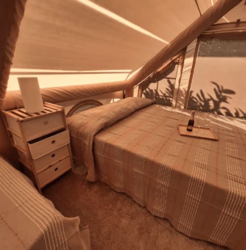 Spaziosa camera familiare in tenda presso Baia Dorica Camping Village a Vittoria con letto, comodino e travi in legno